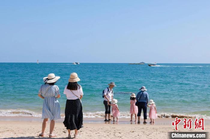 資料圖：家長帶著孩子在海邊嬉浪?！∮谓ㄐ?攝