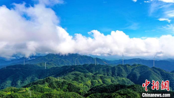 藍(lán)天白云之下，高聳的風(fēng)力發(fā)電機(jī)組與連綿的青山共同構(gòu)成了一幅夏日美景圖?！≈旌ｙi 攝