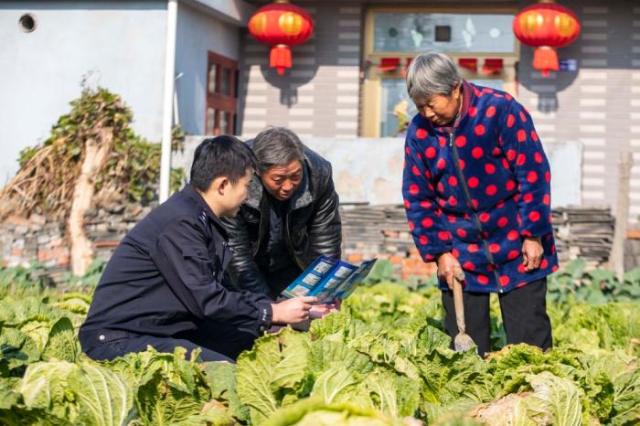 　江蘇省泰州市海陵區(qū)蘇陳派出所民警在蘇陳社區(qū)田間地頭向農(nóng)戶(hù)進(jìn)行普法宣傳(2021年12月4日攝)。新華社發(fā)(湯德宏 攝)