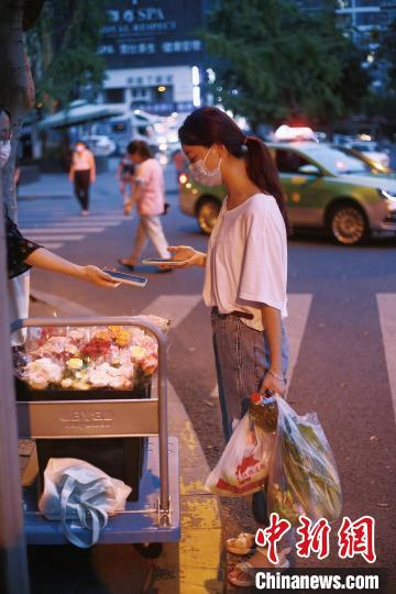 手提兩袋蔬菜的成都市民在選購鮮花?！∈茉L者供圖