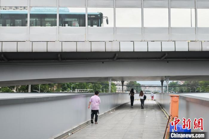圖為市民走在天橋上，公交車從頭頂?shù)缆否傔^?！∨硇拟?攝