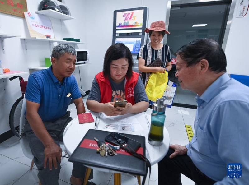 在浙江省杭州市臨安區(qū)玲瓏街道東山社區(qū)便民服務(wù)站，黨員志愿者幫助居民填寫公租房申請(qǐng)資料（2022年8月17日攝）。新華社記者 徐昱 攝