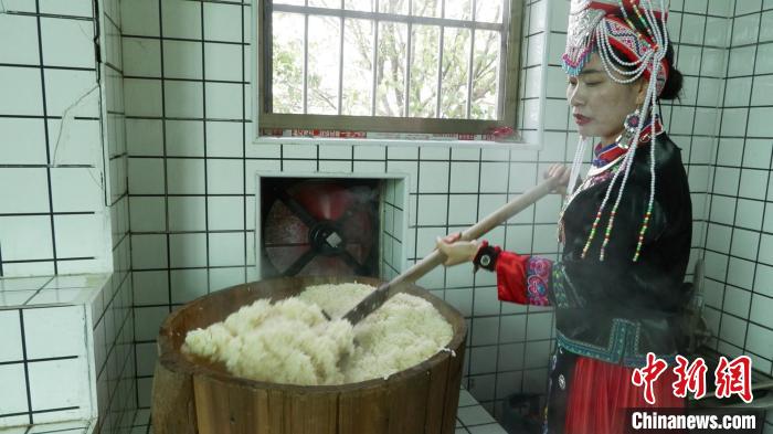 圖為藍春花鏟出煮熟的糯米進行釀酒?！∮浾呷A山 攝