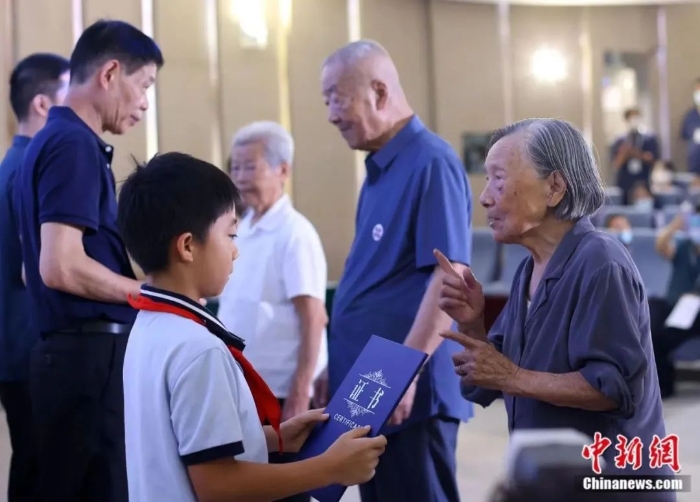 圖片南京大屠殺幸存者夏淑琴(右一)、葛道榮(右二)、艾義英(右三)向南京大屠殺幸存者后代代表頒發(fā)“南京大屠殺歷史記憶傳承人”證書。泱波 攝