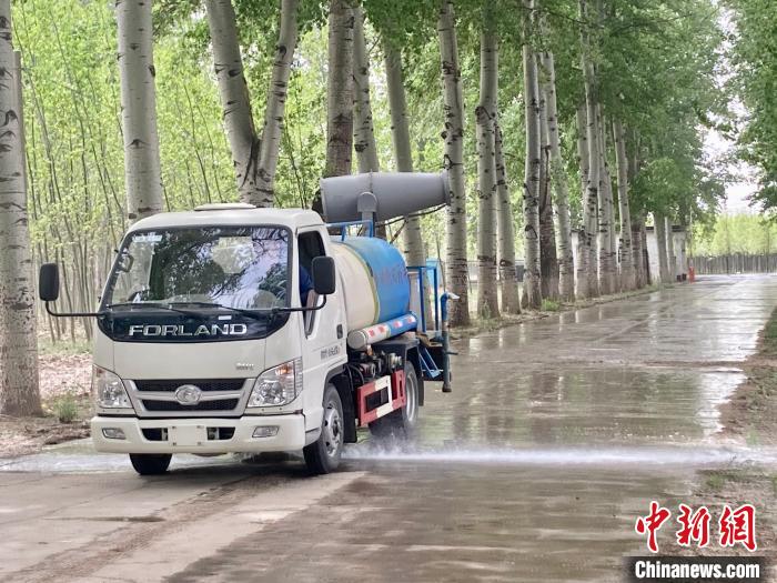 圖為灑水車在對(duì)地面進(jìn)行濕化，降低飄絮強(qiáng)度?！⌒戽?攝