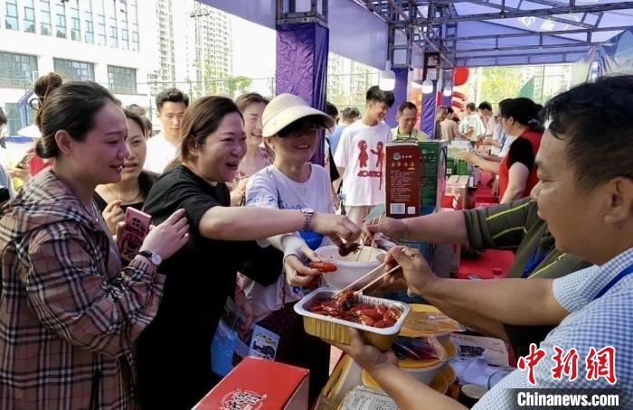 圖為江西南昌英雄城啤酒龍蝦燒烤節(jié)上，游客爭相品嘗鐵河小龍蝦預(yù)制菜?！⌒陆▍^(qū)融媒體中心供圖