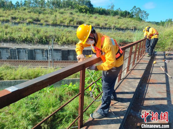 圖為高溫下南寧工務(wù)段橋梁工全副武裝對鐵路橋梁人行道欄桿打磨除銹?！●T博 攝