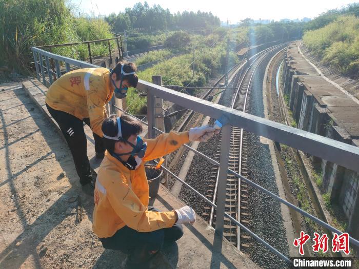 圖為高溫下南寧工務(wù)段橋梁工全副武裝對鐵路橋梁人行道欄桿打磨除銹?！●T博 攝