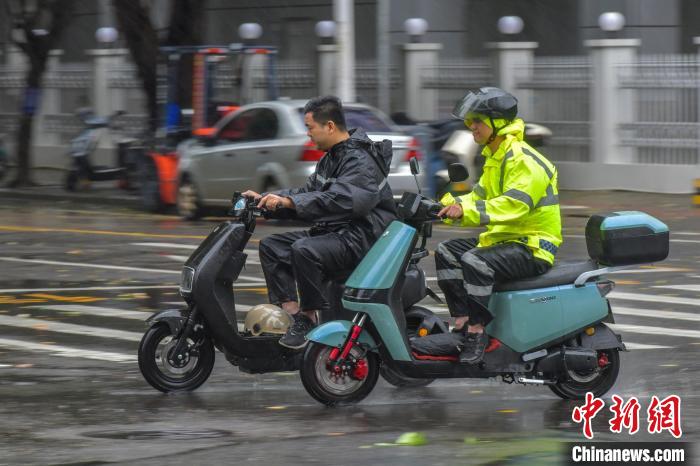 圖為海口市民冒雨出行。　駱云飛 攝