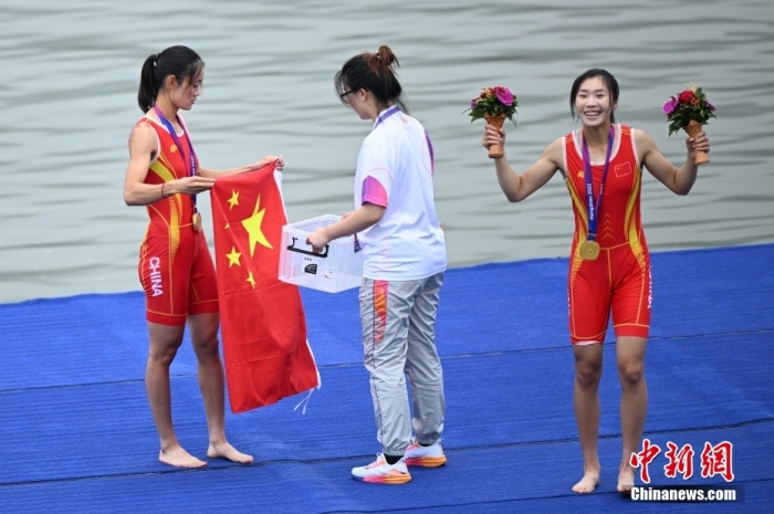 9月24日，杭州第19屆亞運會賽艇女子輕量級雙人雙槳決賽在浙江杭州舉行，中國組合鄒佳琪、邱秀萍以7分06秒78的成績奪冠。這是本屆亞運會的首枚金牌。圖為邱秀萍(左)在頒獎儀式后整理國旗。<a target='_blank' href='/'>中新社</a>記者 王剛 攝