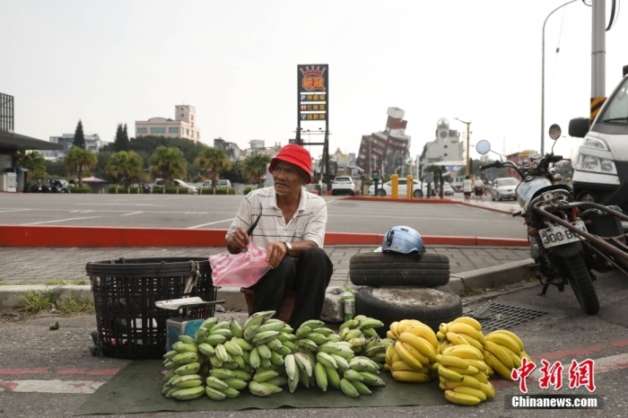 資料圖：臺灣花蓮市區(qū)博愛路早市，商販在街頭擺攤售賣水果，不遠處是因震傾斜嚴重的天王星大樓。 中新社記者 楊程晨 攝.jpg