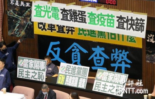 “立院”議場內(nèi)貼滿藍綠白的布條海報，上面寫著“查光電、查疫苗、查快篩”等字